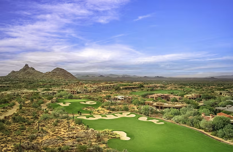 Scenic view of Troon North Golf Club in Scottsdale, AZ, with lush fairways, desert landscape, and distant mountains.